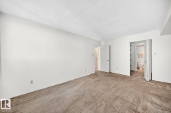 Carpeted room featuring white walls and a white textured ceiling - 