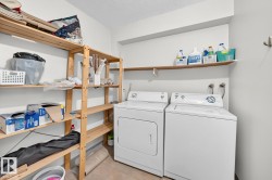Dedicated laundry area featuring a washer and dryer hookup, ample wooden shelving, and a tiled floor - 