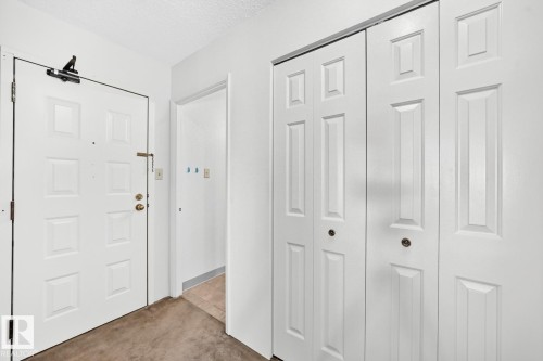Entryway featuring a paneled door, bi-fold closet doors, and wall-to-wall carpeting - 806 10545 Saskatchewan Drive, Edmonton, AB 