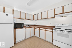 Kitchen featuring wood-frame cabinetry with white panel doors, wood-finish countertops, and a white appliance suite including a refrigerator, dishwasher, and electric range - 