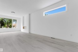 Spacious room featuring light wood-finish flooring, white walls, and a large picture window - 