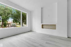 Bright interior with a large picture window, light wood-finish flooring, and a built-in media niche with an open lower compartment - 