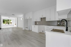Modern kitchen featuring white shaker-style cabinetry, a white countertop, and a gray subway tile backsplash - 