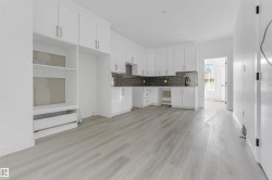 Kitchen area featuring white cabinetry, gold-tone hardware, and a dark subway tile backsplash - 