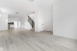 Open-concept living area featuring light wood-finish flooring, white walls, and recessed lighting - 