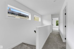 Upper-level hallway featuring plush gray carpeting, white walls, and recessed lighting - 