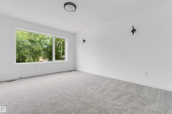 Spacious room featuring a large window, gray carpet, white walls, black wall sconces, and a flush mount ceiling fixture - 