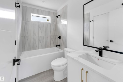 Bathroom featuring a white vanity with a rectangular undermount sink, a countertop, and a matte black faucet - 3605 112 Ave, Edmonton, AB 