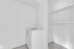 Compact wet bar featuring a white cabinet with gold-toned hardware, an integrated sink, and a stone-finish countertop - 