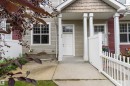 Inviting front entrance featuring a white door with transom window, covered porch, two white support pillars, and a concrete walkway - 73 2051 Towne Centre Boulevard, Edmonton, AB 