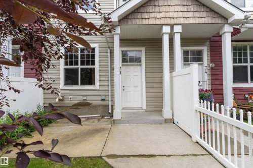 Inviting front entrance featuring a white door with transom window, covered porch, two white support pillars, and a concrete walkway - 73 2051 Towne Centre Boulevard, Edmonton, AB 