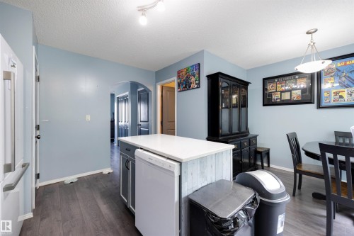 Kitchen featuring an island with a white countertop and wood-finish paneling, dark wood-finish flooring, recessed lighting, and a pendant light fixture - #28 290 Spruce Ridge Rd, Spruce Grove, AB - Indoor Photo Showing Dining Room