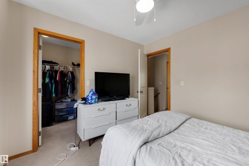 Carpeted room with a ceiling fan, a built-in closet with hanging rods, and a doorway with wood trim - #28 290 Spruce Ridge Rd, Spruce Grove, AB - Indoor Photo Showing Bedroom