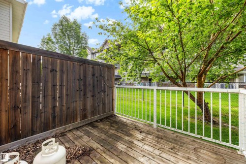 Exterior wood deck with a privacy fence and white railing, overlooking a green lawn with mature trees - #28 290 Spruce Ridge Rd, Spruce Grove, AB - Outdoor With Deck Patio Veranda With Exterior