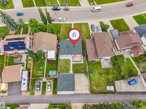 Aerial view of a residential property featuring a dark-colored shingled roof, a rear deck, and a green lawn - 193 Woodvale Road W, Edmonton, AB 