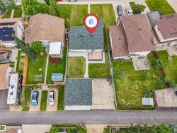 Aerial view showcasing the property with a dark shingle roof and a concrete driveway - 