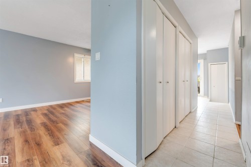 Hallway featuring light-colored tile flooring, white bi-fold closet doors, and light blue wall paint - 193 Woodvale Road W, Edmonton, AB 