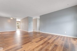 Spacious interior featuring wood-finish flooring, light gray walls, white baseboards, and a ceiling fan - 