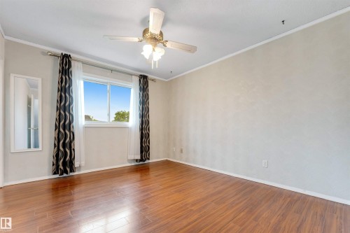 Spacious room featuring wood-finish flooring, a ceiling fan with integrated lighting, and a window providing natural illumination - 193 Woodvale Road W, Edmonton, AB 