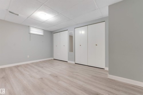 Spacious room featuring light wood-finish flooring, light gray walls, and white baseboards - 193 Woodvale Road W, Edmonton, AB 