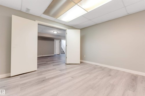 Brightly lit room featuring light wood-finish flooring, neutral wall paint, and white trim - 193 Woodvale Road W, Edmonton, AB 