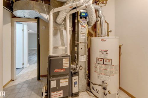 Utility area featuring a water heater and furnace with exposed ductwork, positioned on a tiled floor - 193 Woodvale Road W, Edmonton, AB 