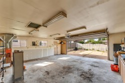 Spacious garage featuring a concrete floor, fluorescent ceiling lighting, and exposed ceiling joists - 
