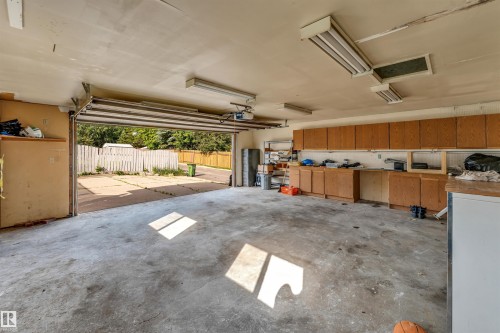 Spacious garage featuring a concrete floor, built-in cabinetry, overhead fluorescent lighting, and an automatic garage door opener - 193 Woodvale Road Nw, Edmonton, AB - Indoor Photo Showing Garage