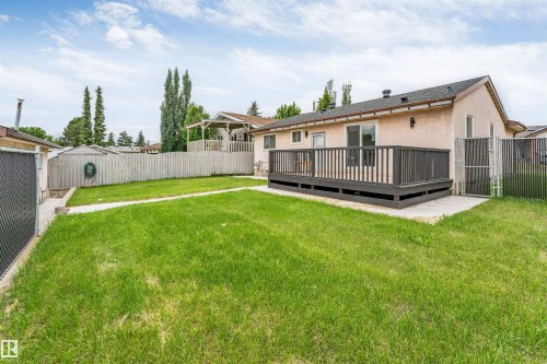 Expansive backyard featuring a large composite deck, mature trees, a wooden privacy fence, and a chain-link fence - 193 Woodvale Road W, Edmonton, AB 