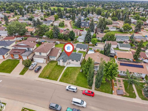Single-family residence featuring a light-colored exterior and a dark shingled roof, surrounded by mature trees and manicured lawns - 193 Woodvale Road W, Edmonton, AB 