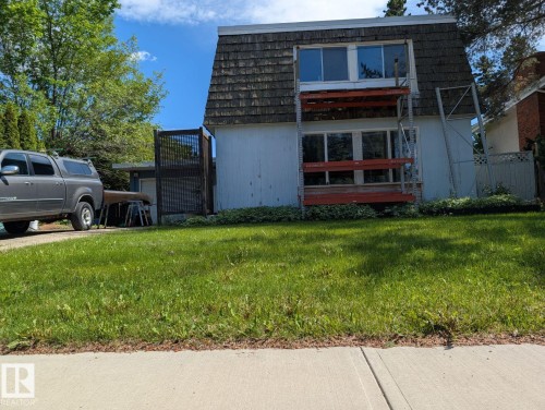 Front exterior featuring a gambrel roofline, white siding, and upper and lower-level windows - 4632 113A Street, Edmonton, AB 