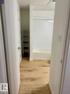 Bathroom featuring a white subway tile surround, a white bathtub, and wood-finish flooring - 