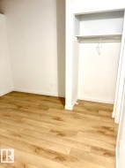 Interior room featuring wood-finish flooring, white baseboards, and a built-in closet with a hanging rod and shelf - 