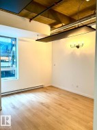 Room featuring wood-finish flooring, a wall-mounted light fixture, and a window providing natural illumination - 