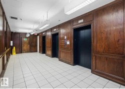 Entryway featuring three elevators with dark doors and wood paneling - 