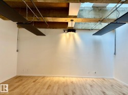 Spacious interior featuring exposed wooden beams and light wood-finish flooring - 
