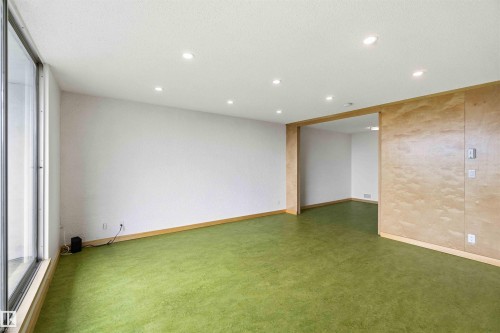 Expansive room featuring wall-to-wall green carpeting, white walls, and recessed lighting - 1008 11307 99 Avenue, Edmonton, AB 