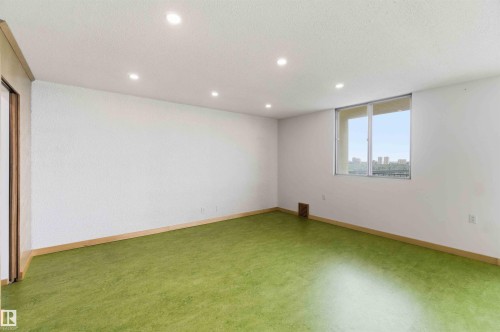 Spacious room featuring a large window, recessed lighting, wood trim, and a sliding door - 1008 11307 99 Avenue, Edmonton, AB 