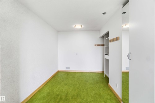 Room featuring green carpet flooring, white walls, and a built-in closet system with open shelving - 1008 11307 99 Avenue, Edmonton, AB 