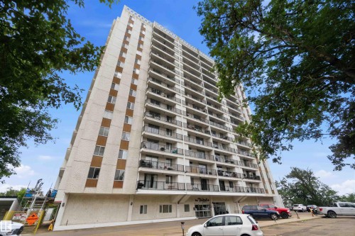 Multi-story building featuring numerous balconies with dark railings, a light-colored facade, and a prominent entrance canopy - 1008 11307 99 Avenue, Edmonton, AB 