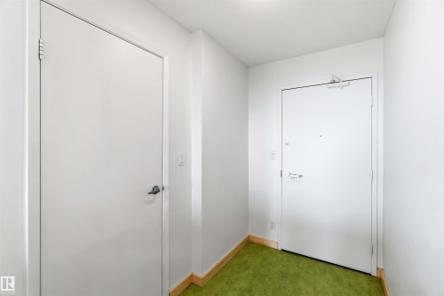 Entryway featuring a white door with a lever handle, white walls, and bright green carpeting - 1008 11307 99 Avenue, Edmonton, AB 
