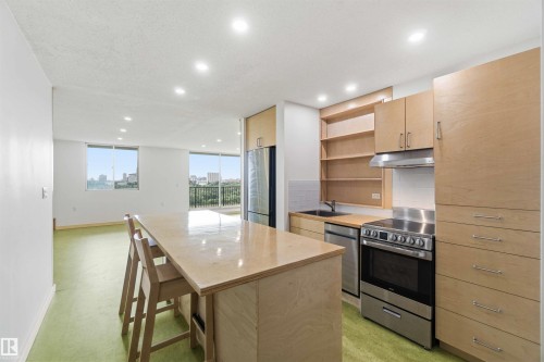 Open-concept kitchen featuring light wood-finish cabinetry, stainless steel appliances, a large center island with seating, recessed lighting, and a white subway tile backsplash - 1008 11307 99 Avenue, Edmonton, AB 
