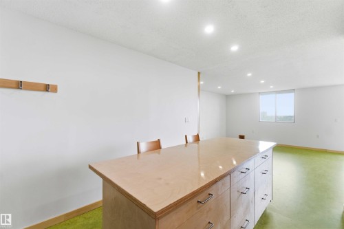 Spacious room featuring a large wood-finish island with multiple drawers and metal hardware - 1008 11307 99 Avenue, Edmonton, AB 