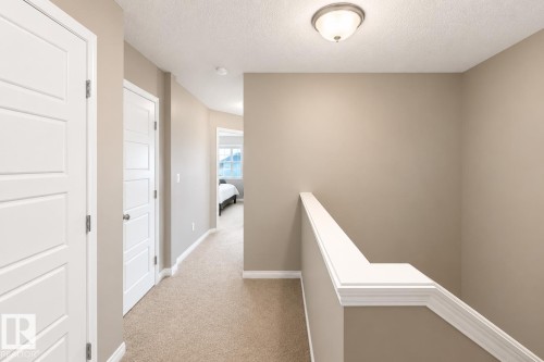 Upper-level hallway featuring neutral wall paint, white trim, and a semi-flush mount ceiling light - 20104 19 Avenue, Edmonton, AB 