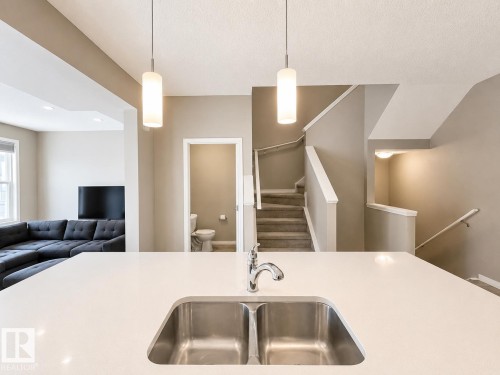 Kitchen island featuring a dual stainless steel sink and a contemporary chrome faucet - 20104 19 Avenue, Edmonton, AB 
