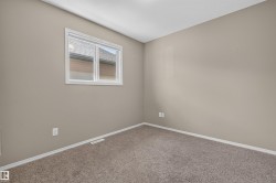 Neutral-toned room featuring a single window with white trim, light brown carpeting, and white baseboards - 
