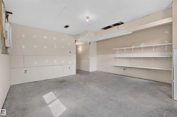 Unfinished interior space featuring a concrete floor, gypsum board walls, and built-in white shelving - 