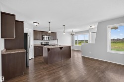 Open-concept kitchen and living area featuring wood-finish flooring, dark wood cabinetry, stainless steel appliances, and a central island with countertop seating - 