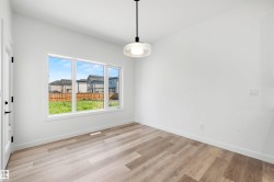 Bright interior space featuring a large three-panel window, wood-finish flooring, and crisp white walls - 