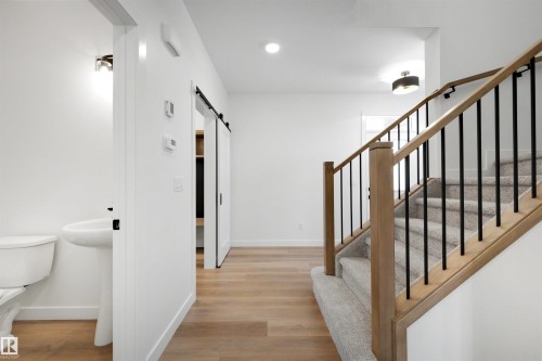 Modern staircase featuring wood-finish handrails and black metal balusters - 30 Elsinore Place, Edmonton, AB 
